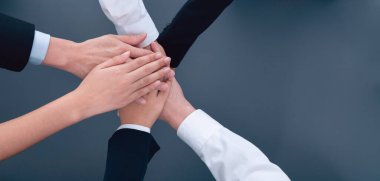Top view partial hands wearing formal suit joining stack and form circle as symbol of team building, unity and harmony in office workplace. Successful business team of synergy holding hand together.