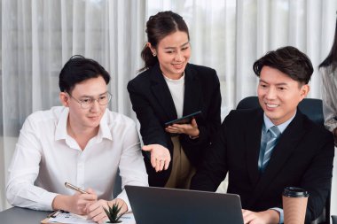 Harmony in office concept as business people analyzing dashboard paper together in workplace. Young colleagues give ideas at manager desk for discussion or strategy planning about project.