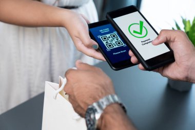 Parasız ödeme taraması için QR kodu ekranda görüntülendi. Kapalı eller, mobil uygulamadan elektronik işlem yoluyla para aktarmak için akıllı telefonu tutuyor. Hızlı ödeme için barkod teknolojisi. Coşkulu