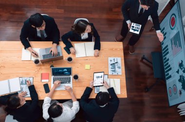 Top view manager or office worker give presentation in harmony conference room to business colleague, BI data dashboard on screen and pile of financial analyzed data reports on meeting table.