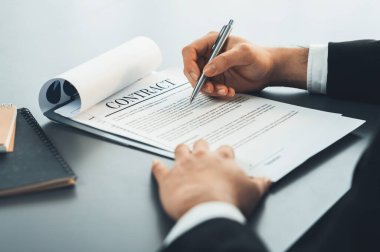 İş adamı sözleşme kağıtlarını ya da iş hukukunu güven ve profesyonellikle imzalar. Resmi iş anlaşması için şirket toplantısında el ele tutuşmak. Eşitlik