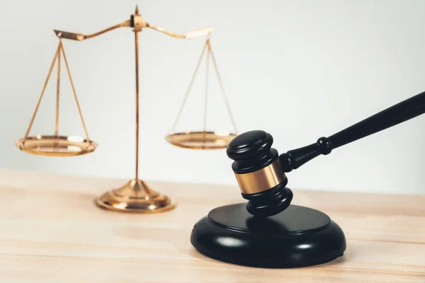 stock image Symbolizing justice and legal authority, golden balanced scale and gavel on desk with law book in lawyer office background, reflecting concept of equality and fair judgment. equility