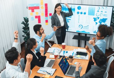 İş adamları TV ekranında başarılı bir sunum veya veri analizi toplantısından sonra kutlama yapıyorlar. Mutlu takım ofis odasında toplanıyor, kutlama jestleriyle işbirliği için tezahürat yapıyorlar. Uyum