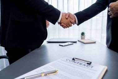 İki profesyonel, yakın el sıkışma ile iş anlaşmasını başarıyla tamamlayarak, ortaklık anlaşmasını imzaladı. Yasal belge ve el sıkışma iki şirket arasında resmi bir anlaşma. Coşkulu