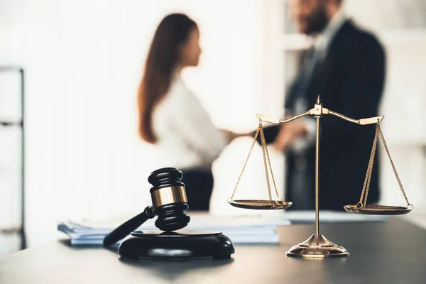 Balanced scale of justice and gavel hammer in focus on blurred background of lawyer colleagues discuss and plan for lawsuit in law firm office, as legal representatives. Equilibrium