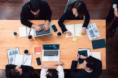Top view manager or office worker give presentation in harmony conference room to business colleague, BI data dashboard on screen and pile of financial analyzed data reports on meeting table.