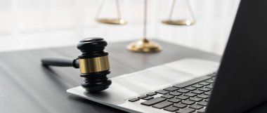 Adalet ve hukuki otoriteyi temsil eden, altın dengeli ölçek ve hukuk bürosunda dizüstü bilgisayarlı tokmak, avukat ve hakimin eşitlik ve adil yargılama kavramını yansıtıyor. denge