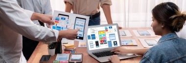 Dizüstü bilgisayar ekranında mobil uygulama için UI ve UX tasarımları tasarlayan ön uç geliştirici ekibin panorama görüntüsü. Kullanıcı dostu UI tasarımı için kullanıcı arayüzü geliştirme ekibi planlama. İnceleyin
