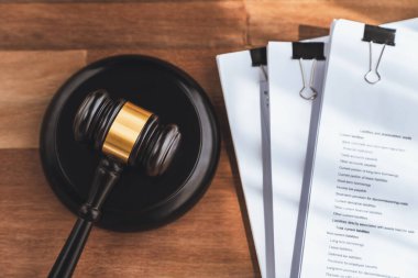 Yakın plan siyah tahta tokmak çekiç ve ahşap ofis masasının arka planındaki yasal belge avukat ve hakim için adalet ve hukuk sistemi, yasal otorite ve mahkemelerde adalet. denge