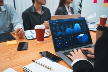 Çok ırklı analist ekibi toplantı masasındaki finansal verileri analiz etmek için BI Fintech yazılımı kullanıyor. Finansal konsol veri ekranında pazarlama göstergesi için analiz edilmiş grafikle birlikte. Uyum