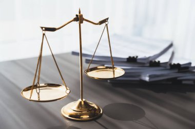 Parlak altın dengeli ölçek ve hukuk bürosundaki yasal kağıt yığını konsept adalet ve hukuki sembol olarak masanın üzerinde. Avukat ve avukatın adil ve eşitlik kararı için terazi uygulayın. denge