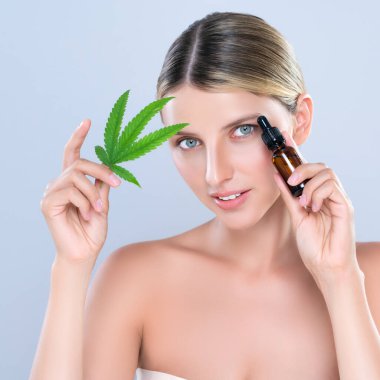 Alluring portrait of beautiful woman in isolated holding green leaf with marijuan extracted bottle for skincare treatment product. Cannabis CBD oil for cosmetology and beauty concept.