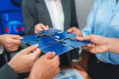 Şirket çalışanı, yapboz parçalarını masa üzerindeki raporlara ortaklık ve takım çalışması olarak bağlıyor. Yapboz 'u birleştirerek iş dünyasındaki birlik ve sinerji. Uyum
