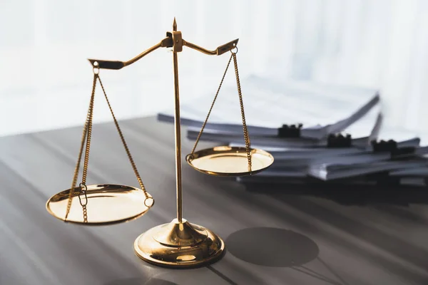 Shiny golden balanced scale and pile of legal paper on desk in lawyer office as concept justice and legal symbol. Scale balance for righteous and equality judgment by lawyer and attorney. equility