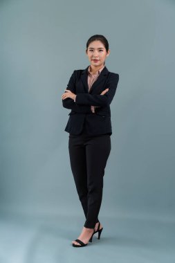 Kendine güvenen genç iş kadınının tüm vücut boyu resmi izole bir arka planda duruyor, resmi siyah takım elbise içinde poz veriyor. Ofisteki kadın ya da yönetici, zeki ve profesyonel görünümlü. Coşkulu.