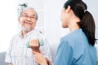 Contented senior patient doing physical therapy with the help of his caregiver. Senior physical therapy, physiotherapy treatment, nursing home for the elderly