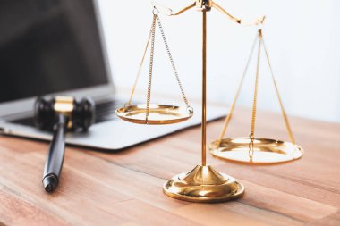 Adalet ve hukuki otoriteyi temsil eden, altın dengeli ölçek ve hukuk bürosunda dizüstü bilgisayarlı tokmak, avukat ve hakimin eşitlik ve adil yargılama kavramını yansıtıyor. denge