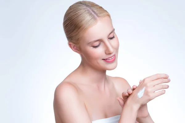 stock image Personable woman applying moisturizer cream on her hand for perfect skincare treatment concept in isolated background. Beauty care cream applying on body by female model with soft natural makeup.