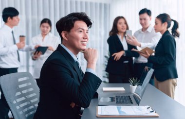 Portrait of focus young successful confident male manager, executive wearing business wear in harmony office arm crossed with blurred meeting background of colleagues, office worker.