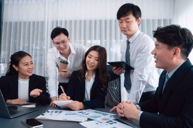 Harmony in office concept as business people analyzing dashboard paper together in workplace. Young colleagues give ideas at manager desk for discussion or strategy planning about project.