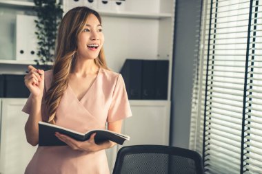 Young competent office lady, intern, secretary holding a log in office room. Concept of various career for office working. Concept of diverse office careers.