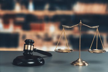 Hukuk firmasında ya da avukatlık bürosunda adalet ve ortak bir hukuki sembol olarak parlak altın dengeli bir ölçek ve ahşap tokmak. Doğruluk ve eşitlik için teraziyi tartın. Eşitlik