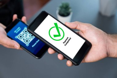 Parasız ödeme taraması için QR kodu ekranda görüntülendi. Kapalı eller, mobil uygulamadan elektronik işlem yoluyla para aktarmak için akıllı telefonu tutuyor. Hızlı ödeme için barkod teknolojisi. Coşkulu