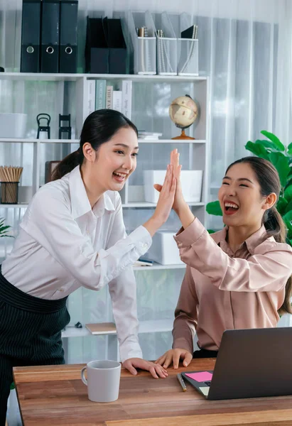Colleagues in the office workspace give high-five to celebrate completing a project or finding a solution to a problem, showcasing a strong sense of teamwork and friendship in workplace. Enthusiastic