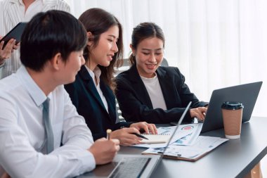 Harmony in office concept as business people analyzing dashboard paper together in workplace. Young colleagues give ideas at manager desk for discussion or strategy planning about project.