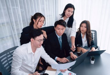 Harmony in office concept as business people analyzing dashboard paper together in workplace. Young colleagues give ideas at manager desk for discussion or strategy planning about project.