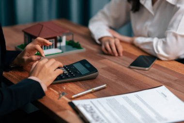 Temsilciyle ev kredisi sözleşmesini gözden geçiriyorum. Mali belgeleri ve vergi oranlarını, mülkiyet sahibi olmak için hesap makinesiyle analiz ediyorum. Yeni ev alımı ve finansman için anahtar imza. Coşkulu.