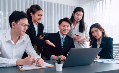 Harmony in office concept as business people analyzing dashboard paper together in workplace. Young colleagues give ideas at manager desk for discussion or strategy planning about project.