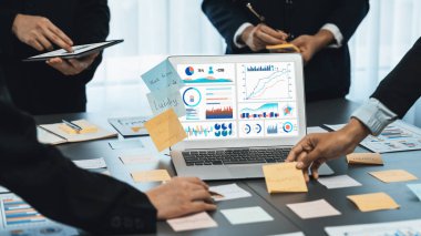 Analizci ekibi yaratıcı ve analitik beyin fırtınası fikri için bilgisayar ekranında BI veri paneli olan yapışkan bir not kullanıyor. Pazarlama stratejisi için finansal veri görselleştirme teknolojisini analiz et. Dahi.