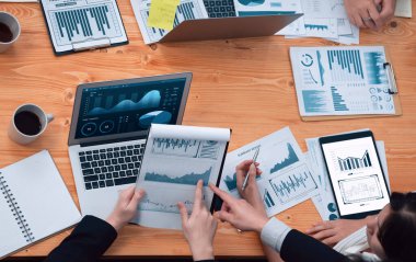 Top-view closeup business team of financial data analysis meeting with business intelligence, report paper and dashboard on laptop. Business group people working together in harmony office.