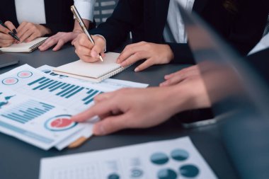 Closeup on BI dashboard on meeting desk with businesspeople analyzing or planning business strategy with hands pointing on financial paper reports as concept of harmony in office workplace.