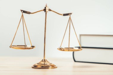 Hukuk fakültesinde adalet ve hukuki sembol olarak masanın üzerinde parlak altın dengeli bir terazi ve hukuk kitabı vardı. Avukat ve avukatın adil ve eşitlik kararı için terazi uygulayın. denge