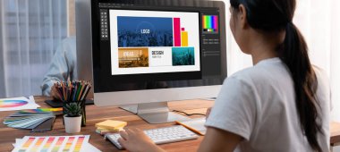 Grafik tasarımcısı, modern dijital stüdyo işyerinde profesyonel grafik ekibiyle benzersiz bir tasarım yaparken bilgisayar dizüstü bilgisayar ve grafik çizim kalemi üzerinde çalışır. Panorama çekimi. İnceleyin