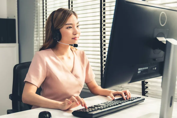 Competent female operator working on computer and while talking with clients. Concept relevant to both call centers and customer service offices.