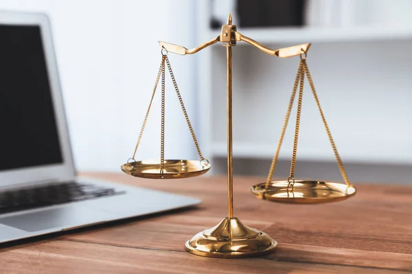 Symbolizing justice and legal authority, golden balanced scale on desk with laptop in law office background, reflecting concept of equality and fair judgment by lawyer and judge. equility