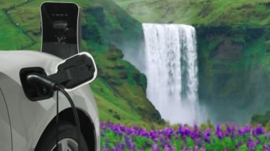 Elektrikli araba, doğal ortam, şelale ve akış arkaplanındaki şarj istasyonundan enerji yüklüyor. Yenilenebilir enerji kaynaklı EV otomobillerin enerji sürdürülebilirliği kavramı.