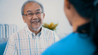 A young female doctor inquires about personal information of a contented senior at home. Medical care for the elderly, elderly illness, and nursing homes, home care.