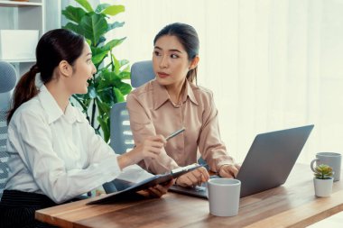 Modern ofis çalışma alanında iş birliği yapan iki genç ofis çalışanı, modern ofis çalışanı olarak profesyonelliklerini sergileyerek, dizüstü bilgisayarda tartışıyorlar ve birlikte çalışıyorlar. Coşkulu.