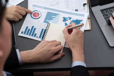 Closeup on BI dashboard on meeting desk with businesspeople analyzing or planning business strategy with hands pointing on financial paper reports as concept of harmony in office workplace.