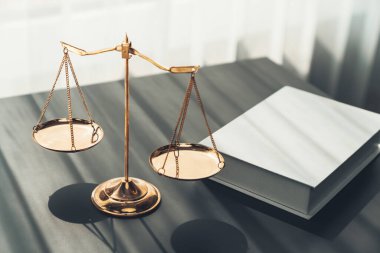 Hukuk fakültesinde adalet ve hukuki sembol olarak masanın üzerinde parlak altın dengeli bir terazi ve hukuk kitabı vardı. Avukat ve avukatın adil ve eşitlik kararı için terazi uygulayın. denge