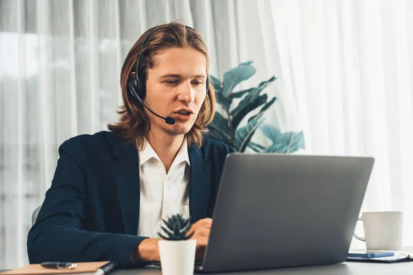 Male customer service operator or telesales agent sitting at desk in office, wearing headset and engage in conversation with client to provide support or close sales. Call center portrait. Entity