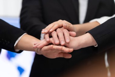 Top view closeup business team of suit-clad businesspeople join hand stack together. Colleague collaborate and work together to promote harmony and teamwork concept in office workplace.