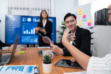 Confidence and young asian businesswoman give presentation on financial business strategy in dashboard report display on screen to colleagues in conference room meeting as harmony in workplace concept