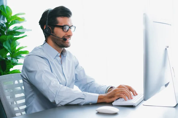 stock image Male call center operator or telesales representative siting at his office desk wearing headset and engaged in conversation with client providing customer service support or making a sale. fervent