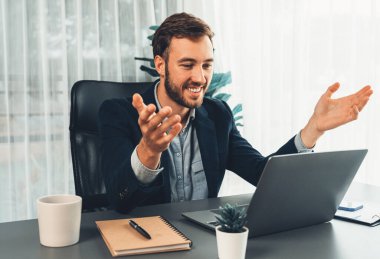 İşadamı ofis masasından sanal ofis toplantısı düzenliyor ve uzaktan çalışanlarla uzak iletişim kurmak için dizüstü bilgisayardaki Webinar uygulamasını kullanarak çevrimiçi video konferansını tartışıyor. Varlık