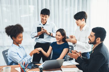 Çeşitli iş arkadaşları başarıyı şirket işyerindeki el sıkışma ve takım çalışmasıyla kutluyor. Çok kültürlü, mutlu profesyonellerden oluşan bir ekip ofiste tokalaşarak birlik oldular. Uyum